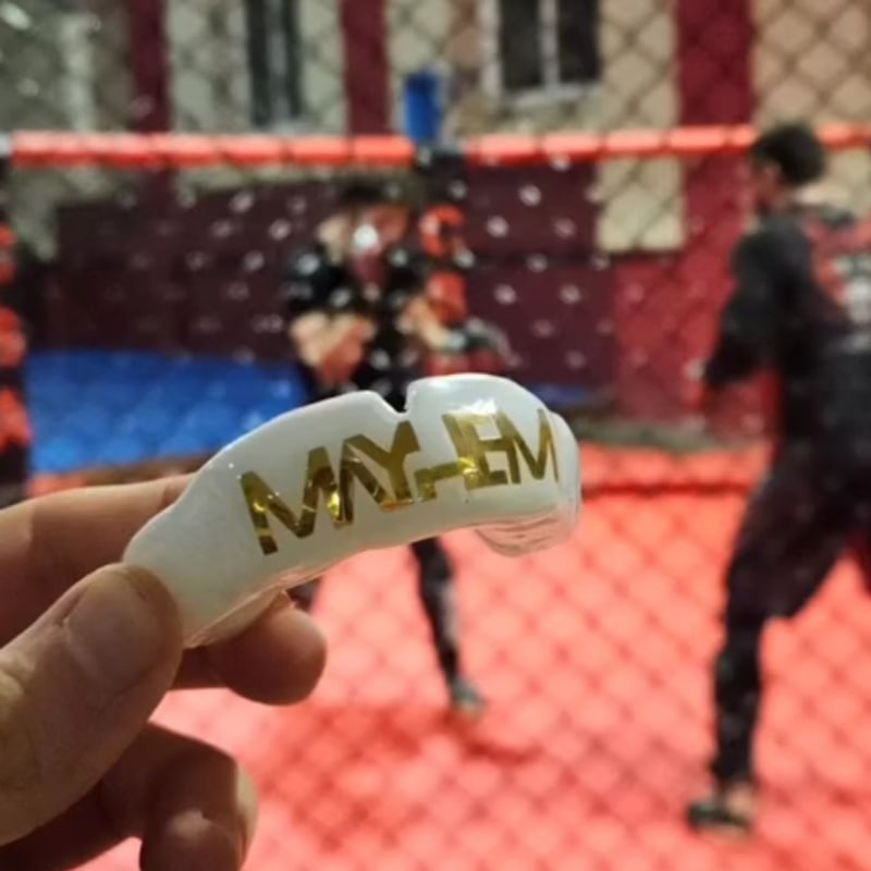 Protège-dents Mayhem tenu devant une cage